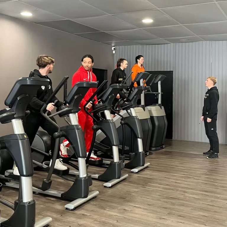 Quatre personnes sur des vélos elliptiques en salle de sport.